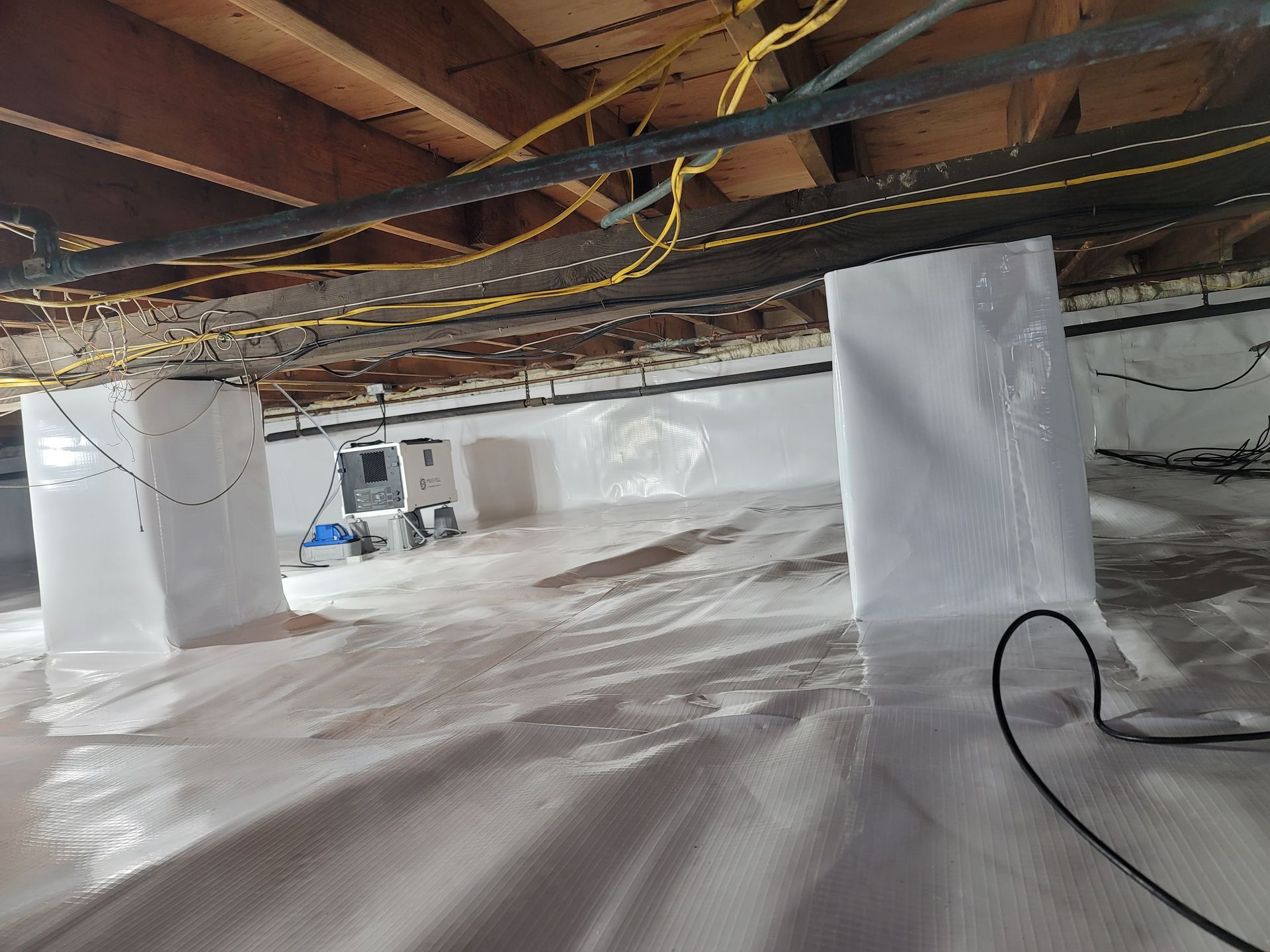 A basement with a lot of electrical wires hanging from the ceiling.