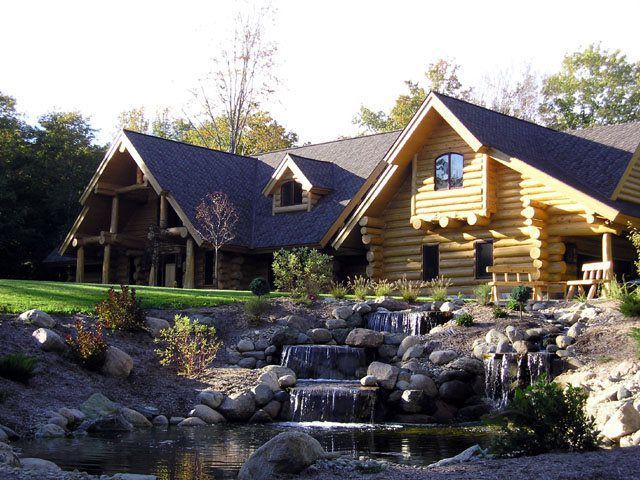 Log cabin home with waterfalls and landscaping.