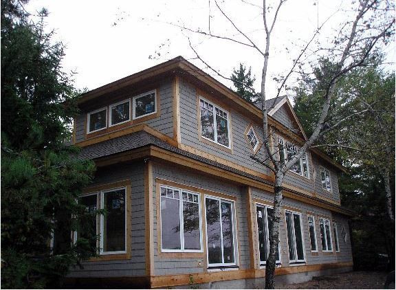 Two-story house with gray siding, large windows, and tan trim. 