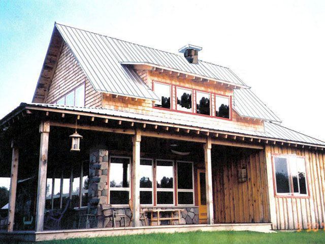 Rustic wooden house with porch and stone accent, metal roof.