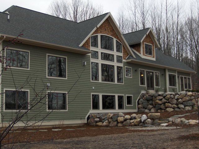 Green house with stone wall and large windows.
