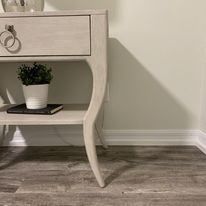 A nightstand with a potted plant and a book on it.