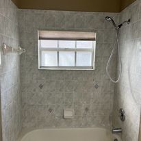A bathroom with a tub , shower , and window.