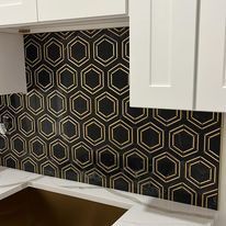 A kitchen with a black and gold hexagon tile backsplash.