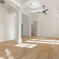 A large empty room with hardwood floors and a ceiling fan.