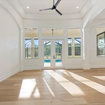An empty living room with hardwood floors and a ceiling fan.