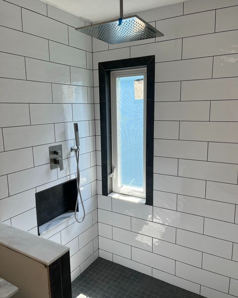 A bathroom with white tiles and a window