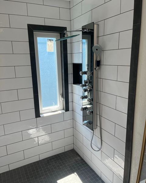 A bathroom with white tiles and a shower head