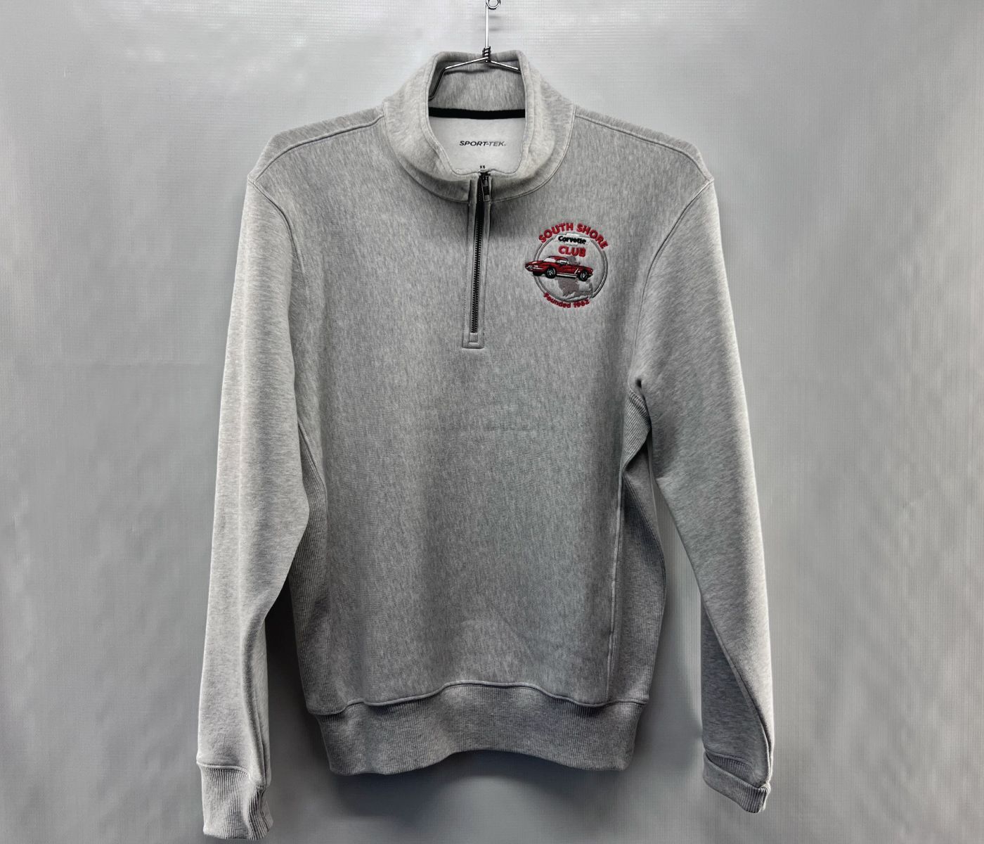 Custom embroidery featuring Gray quarter-zip sweatshirt with a red and brown logo on the chest, hanging against a plain background.
