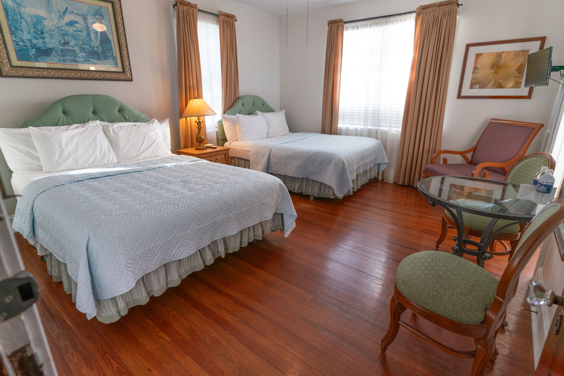 A hotel room with two beds , a chair , and a table.