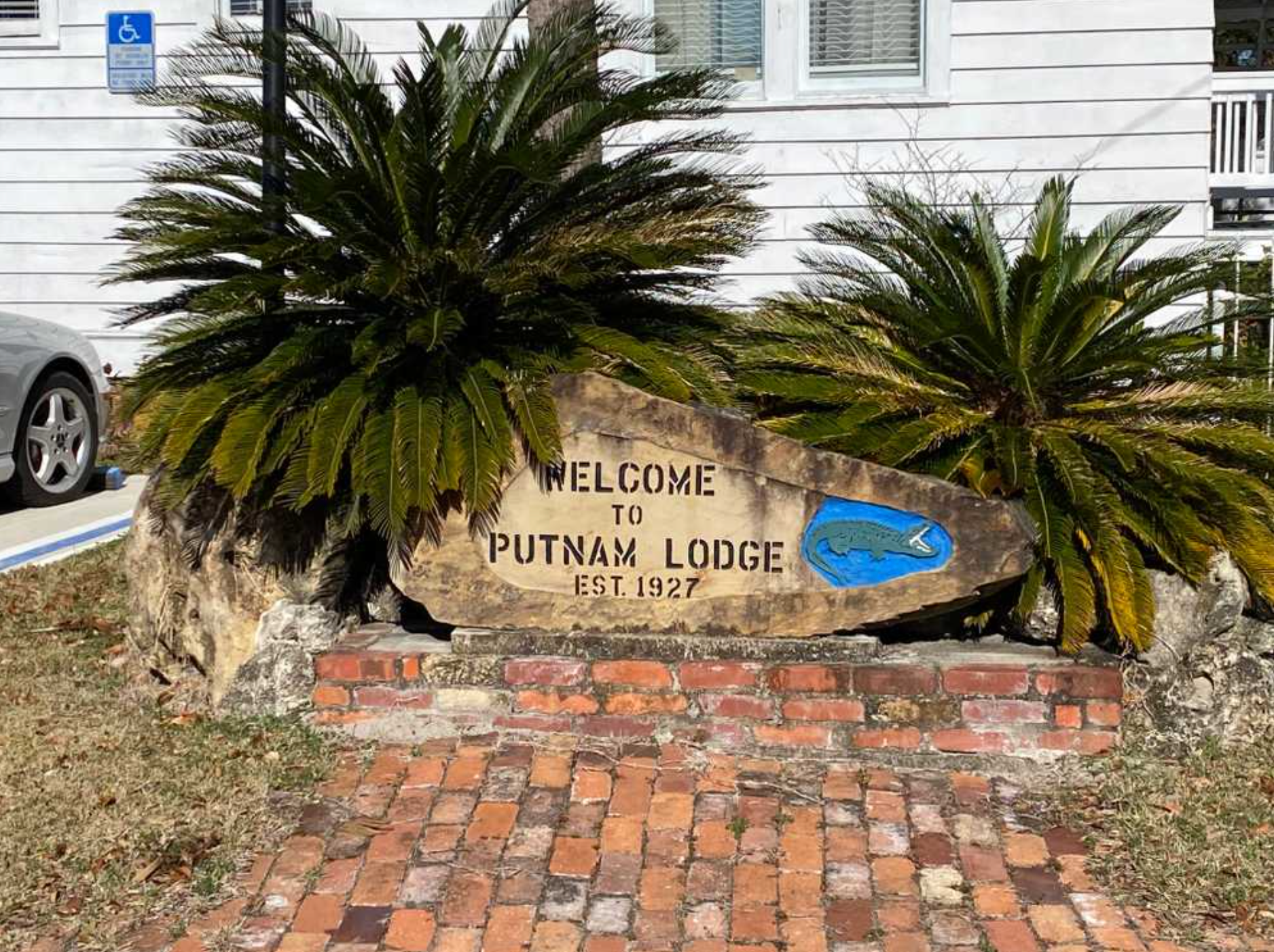 A welcome sign for putnam lodge is sitting on a brick walkway in front of a building.
