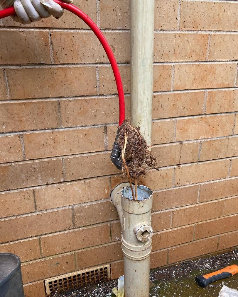 Person is Holding a Red Hose Next to a Drain Pipe — ASAP Local Plumbing in Warrnambool, VIC