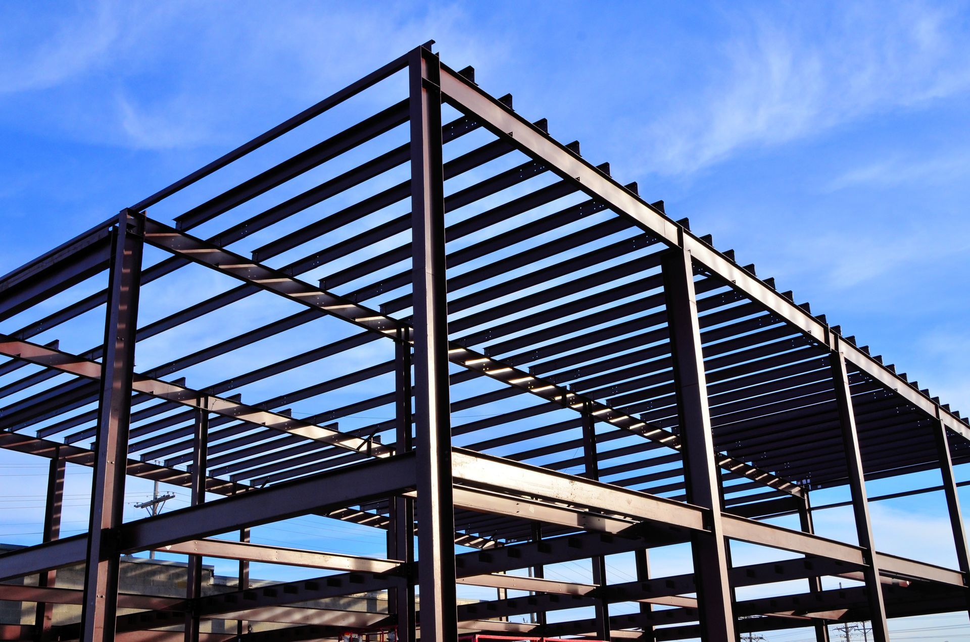 Steel framework of a building under construction against a bright blue sky.