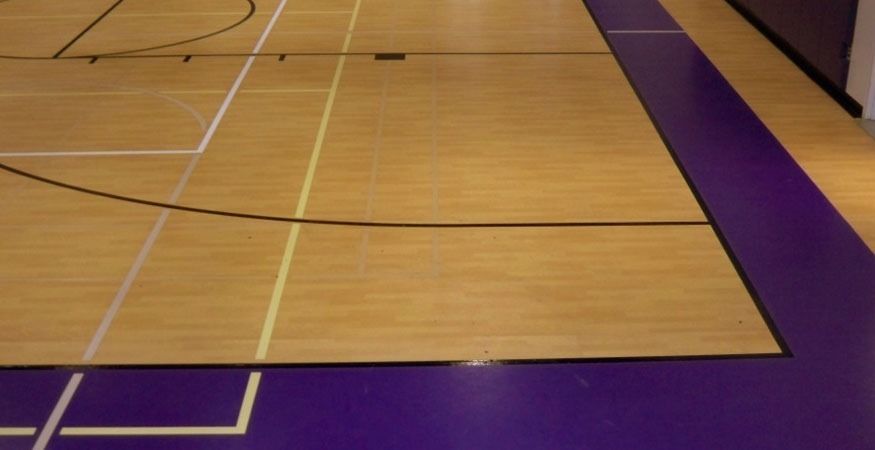 A wooden basketball court with a purple line, on a Hart's Athletic installed floor.