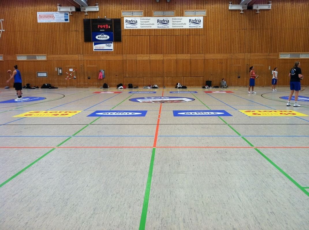 A group of people are playing a game of basketball in a gym, on a Hart's Athletic installed floor.