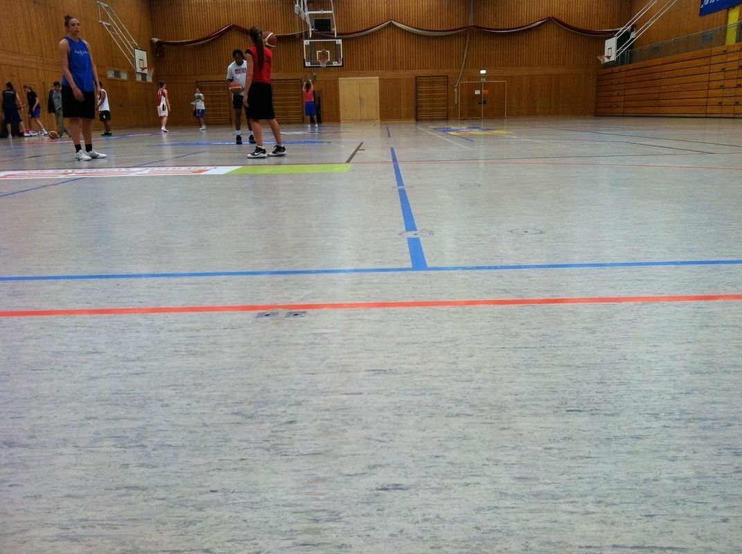 A group of people are playing basketball in a gym, on a Hart's Athletic installed floor.