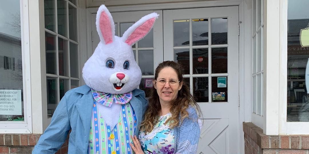 A woman is standing next to a man dressed as an easter bunny.