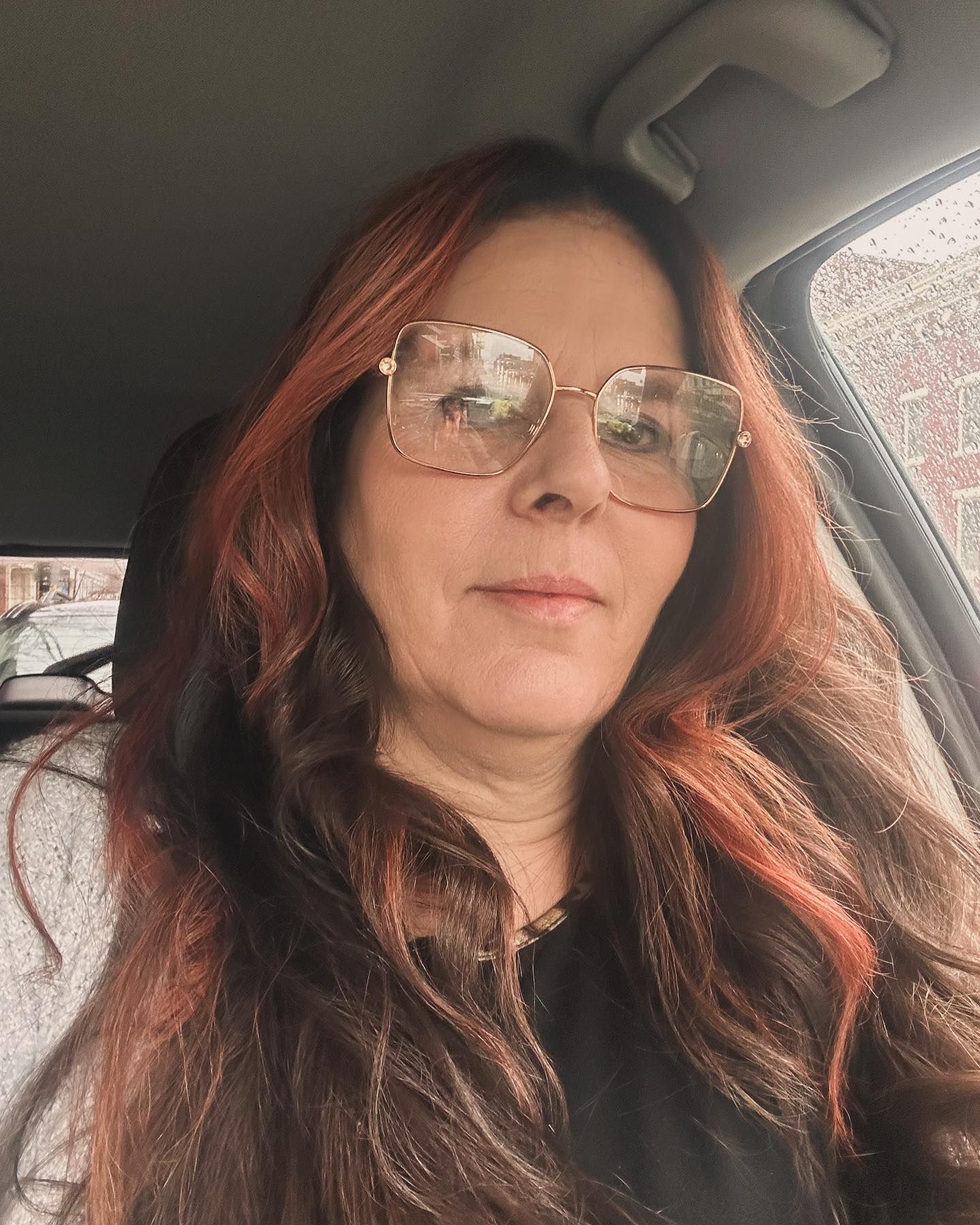 A woman wearing glasses is sitting in a car.