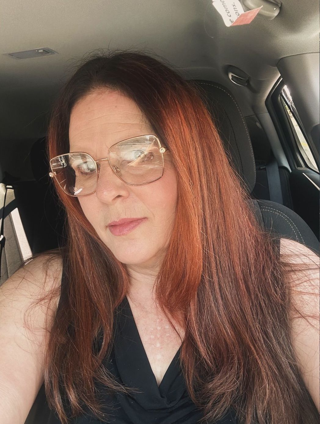 A woman wearing sunglasses is sitting in a car.