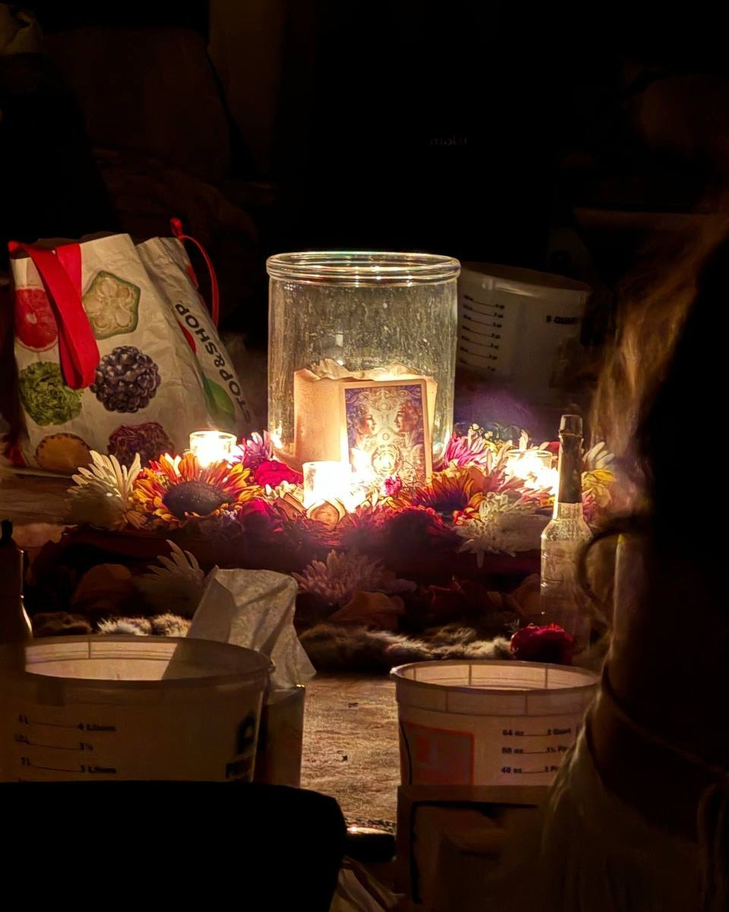 A group of people are sitting around a table with candles and flowers.