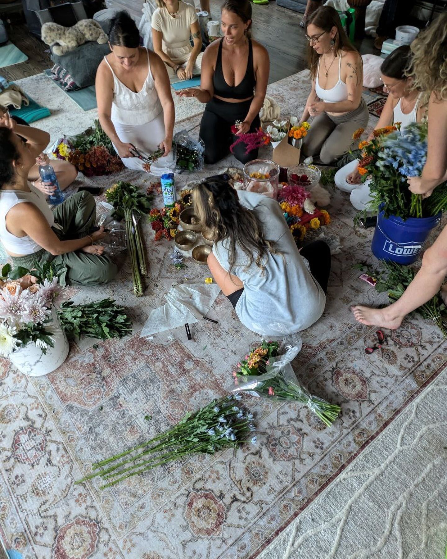 A group of women are sitting around a table with flowers.