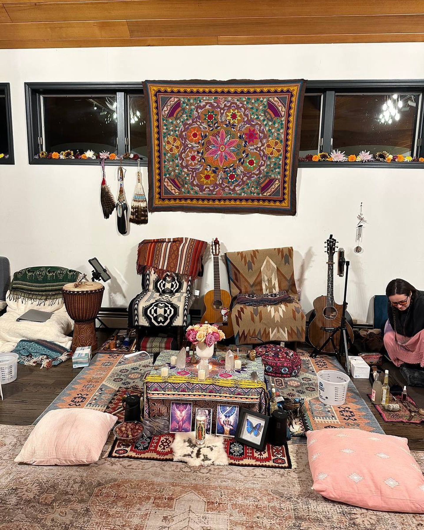A woman is sitting on the floor in a room with a table and chairs.