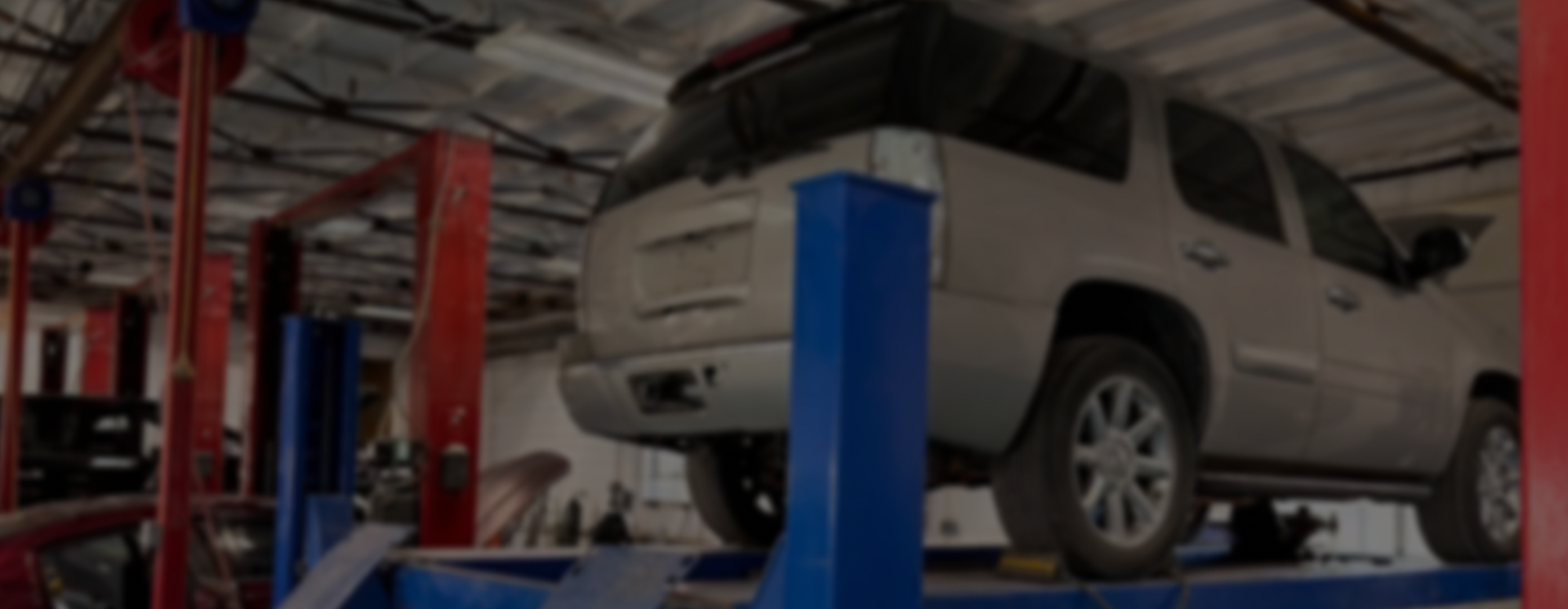 A silver SUV on an auto lift inside a vehicle repair shop | Depot Auto Repair