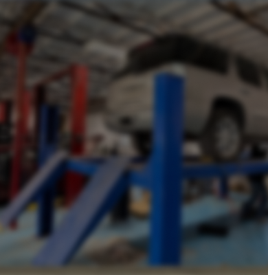 A vehicle lifted on a blue and red hydraulic maintenance rack inside an automotive repair shop | Depot Auto Repair
