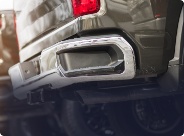 Close-up of a modern truck's rear bumper, highlighting the integrated chrome exhaust port and tail light. | Depot Auto Repair