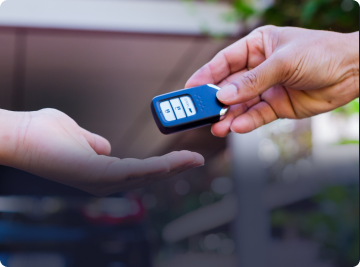 One hand hands a black car key fob to another person's open palm. | Depot Auto Repair