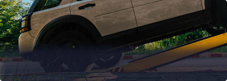 A gloved hand holds a rusty metal shock absorber with a red coil spring in a workshop setting | Depot Auto Repair