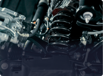 A close-up view of a vehicle's suspension system, featuring a black coil spring and metal mechanical components | Depot Auto Repair