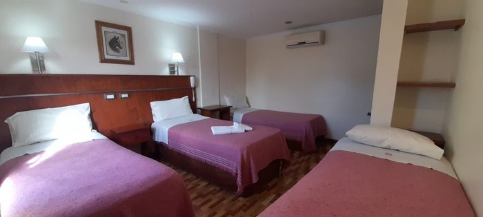 Una habitación de hotel superior con cuatros camas, un cuadro en la pared y aire acondicionado.