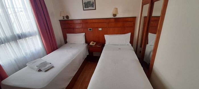 Una habitación de hotel con dos camas individuales y un espejo.