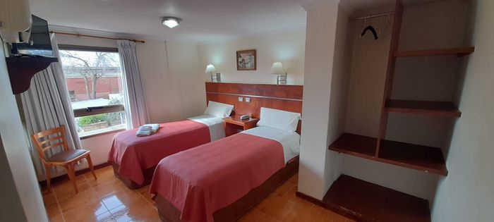 Una habitación superior del hotel con dos camas individuales y una silla y placard.