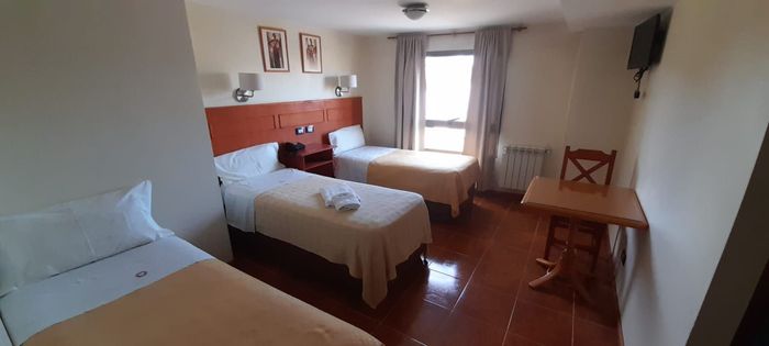 Una habitación superior de hotel con tres camas y una mesa.