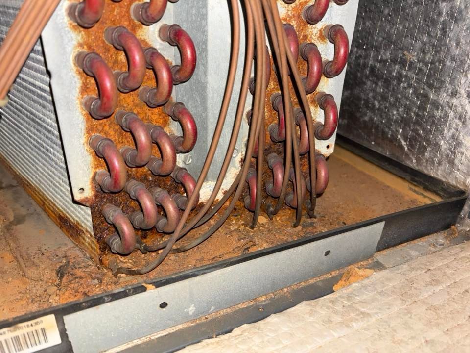 Corroded HVAC evaporator coil in a tray, showing extensive rust and deterioration.