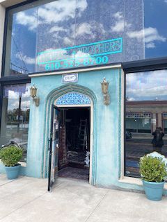 A blue building with a door open and plants in front of it.