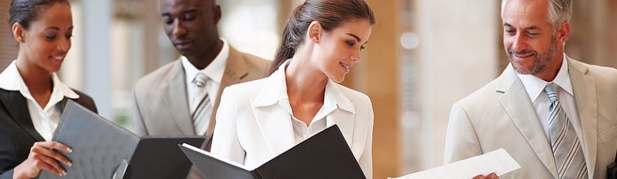 A group of business people are standing around looking at papers.