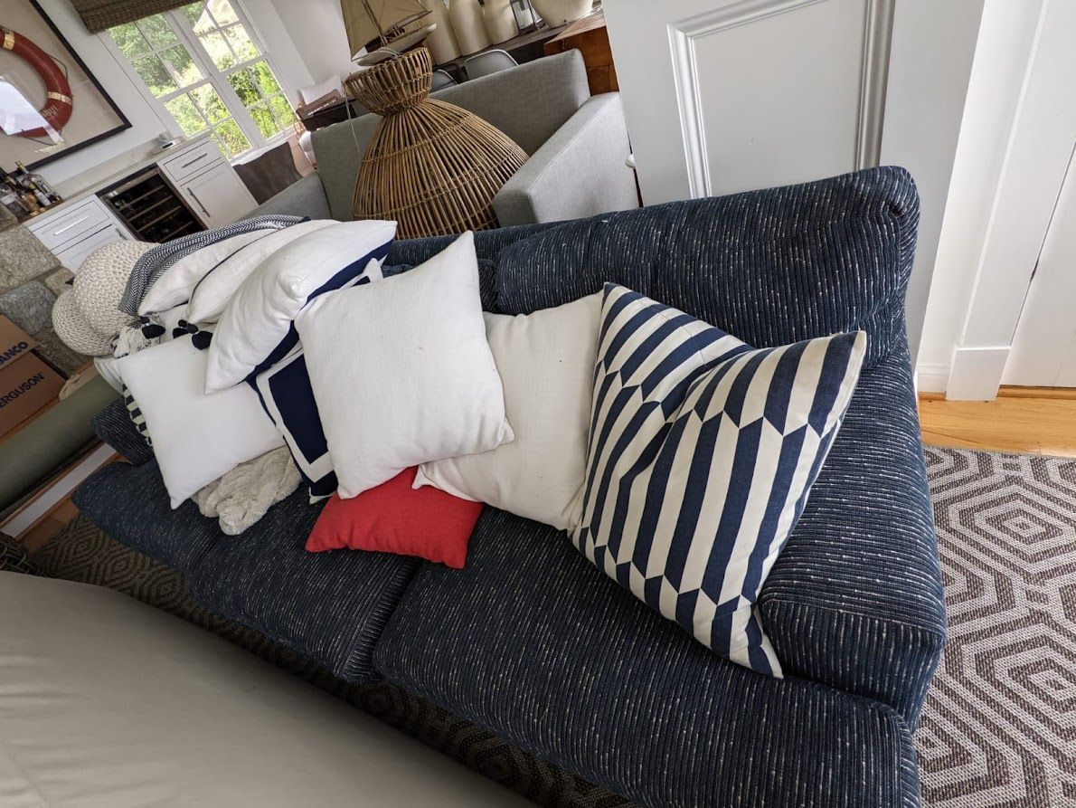 A blue patterned sofa with white and blue pillows in a living room setting.