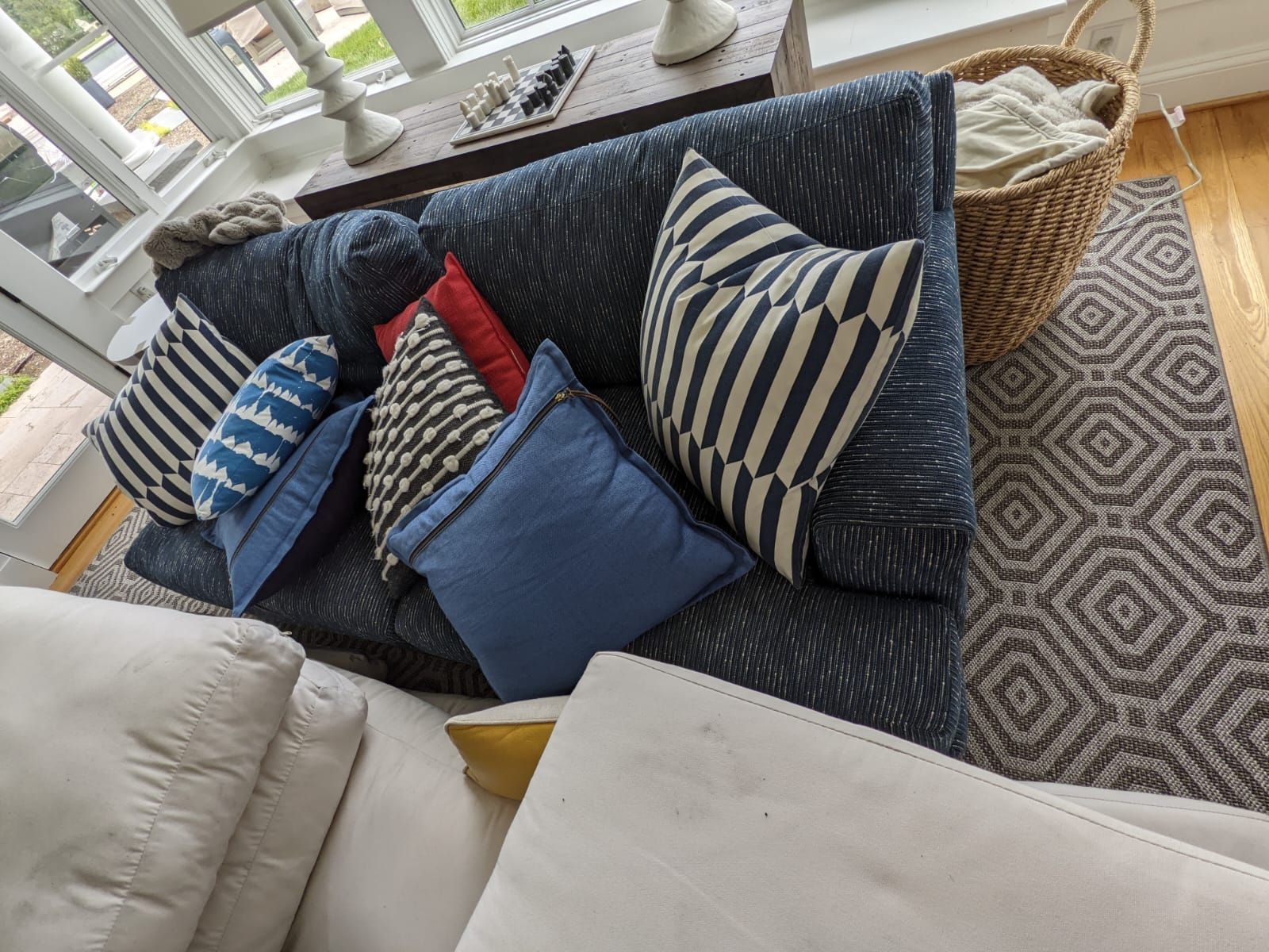 Blue sofa with patterned pillows and a woven basket, next to a patterned rug.