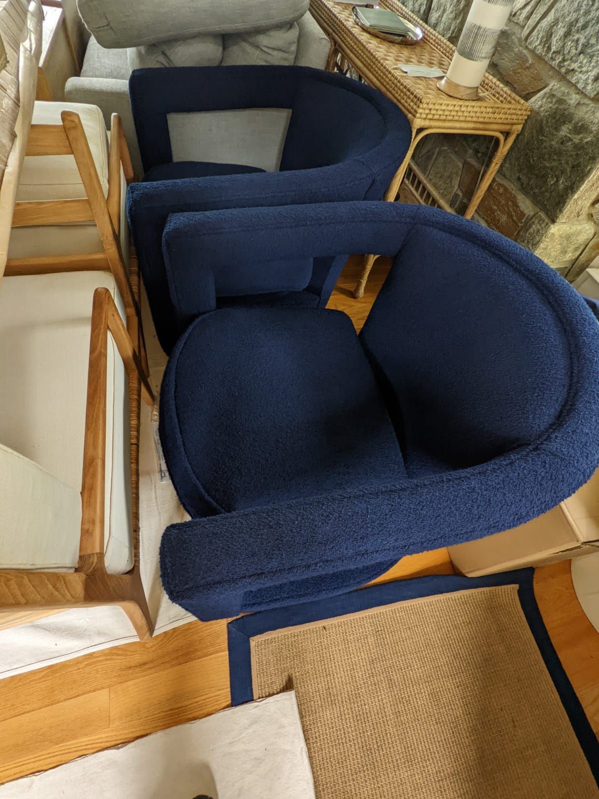 Two navy blue upholstered armchairs, a tan rug, and light wooden chairs.