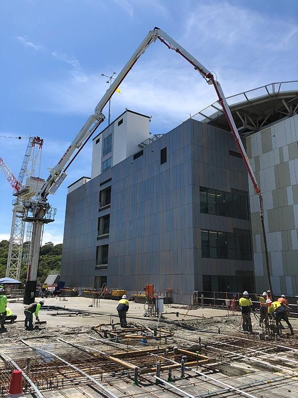 A large building is being built with a concrete pump.