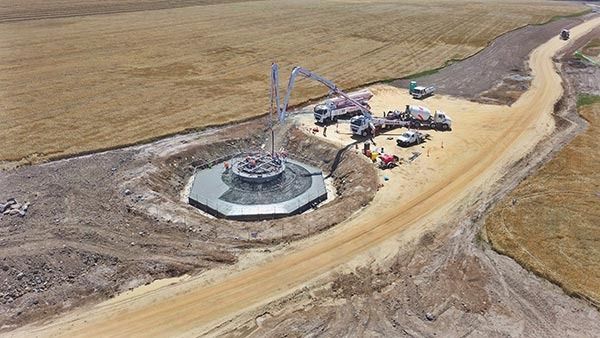 An aerial view of a wind turbine being built on a dirt road.