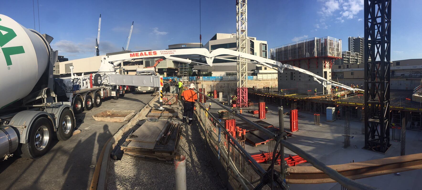 A concrete mixer truck is driving down a road next to a construction site.