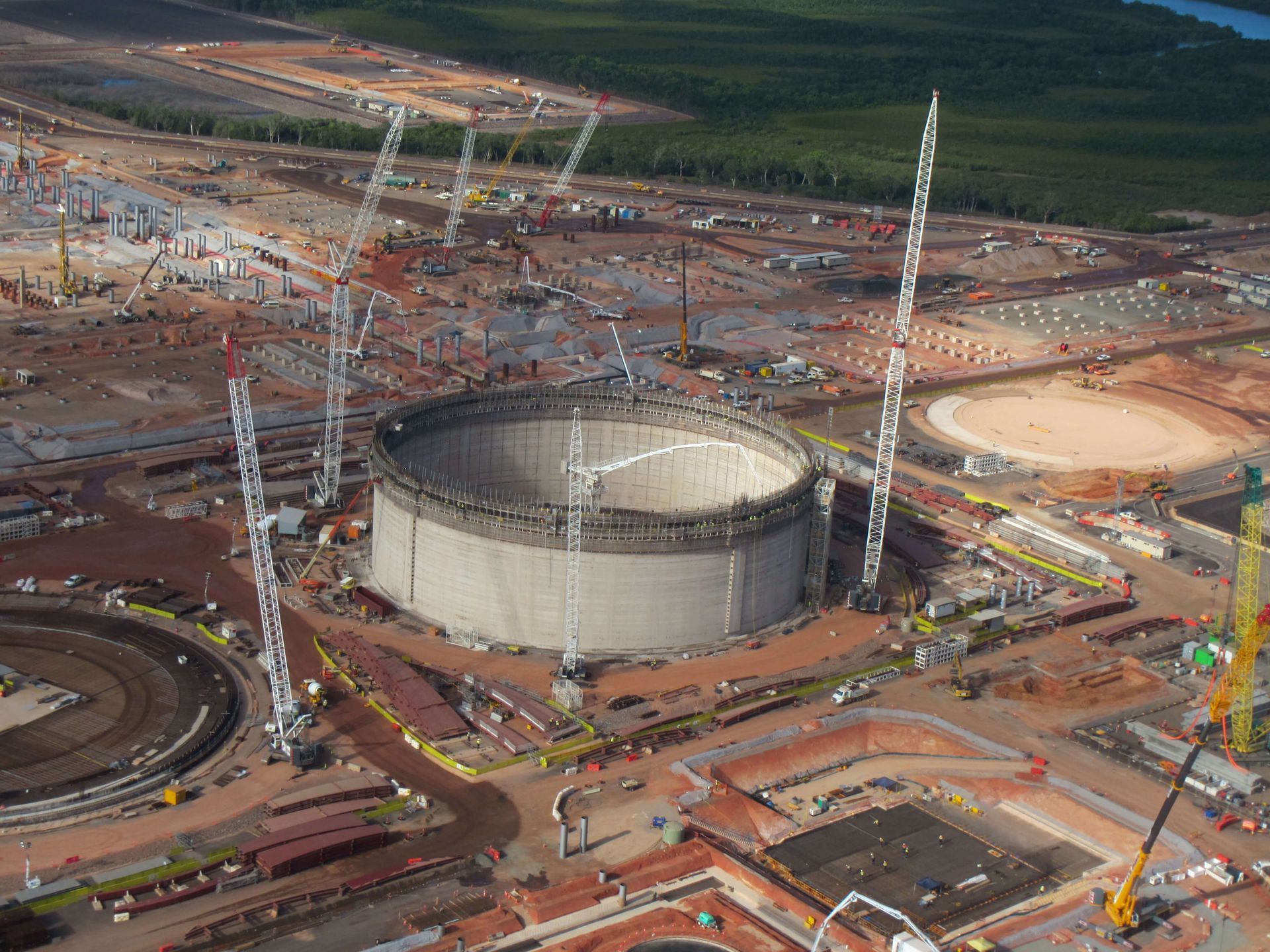 An aerial view of a construction site with a large tank in the middle.