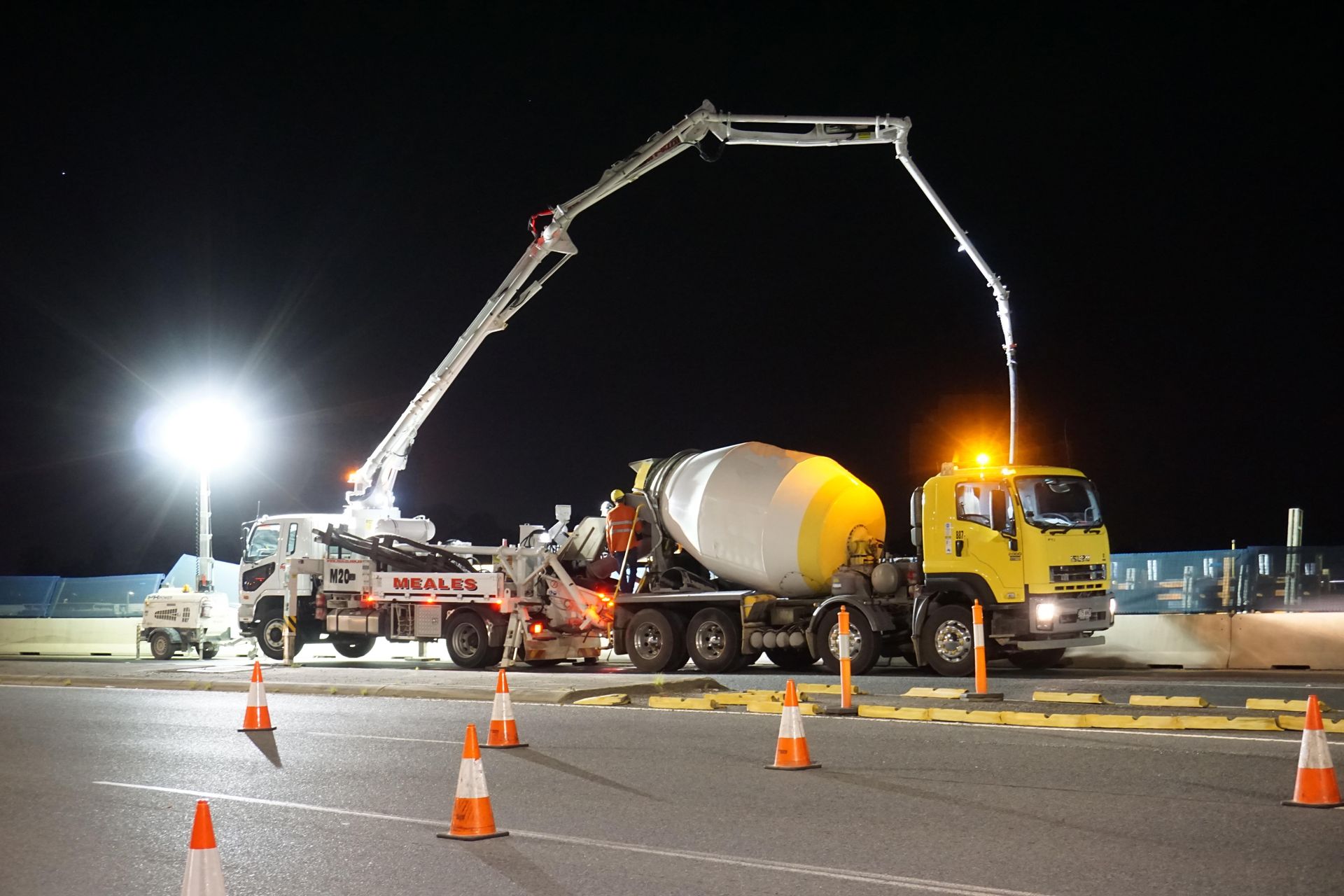 A concrete mixer truck is pumping concrete into the ground at night