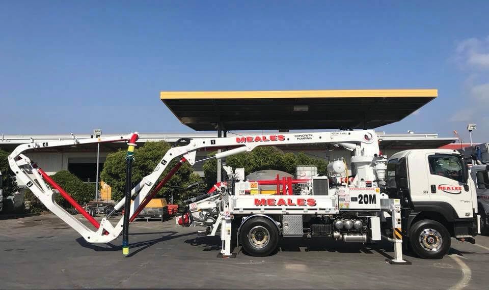 A white truck with a concrete pump attached to it is parked in a parking lot.