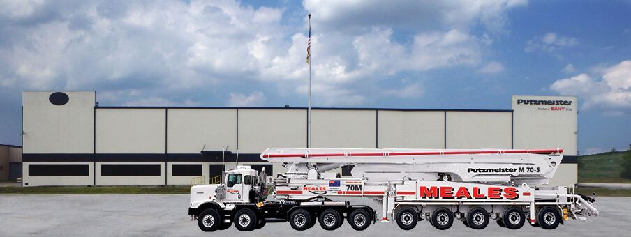 A concrete pump truck is parked in front of a building.