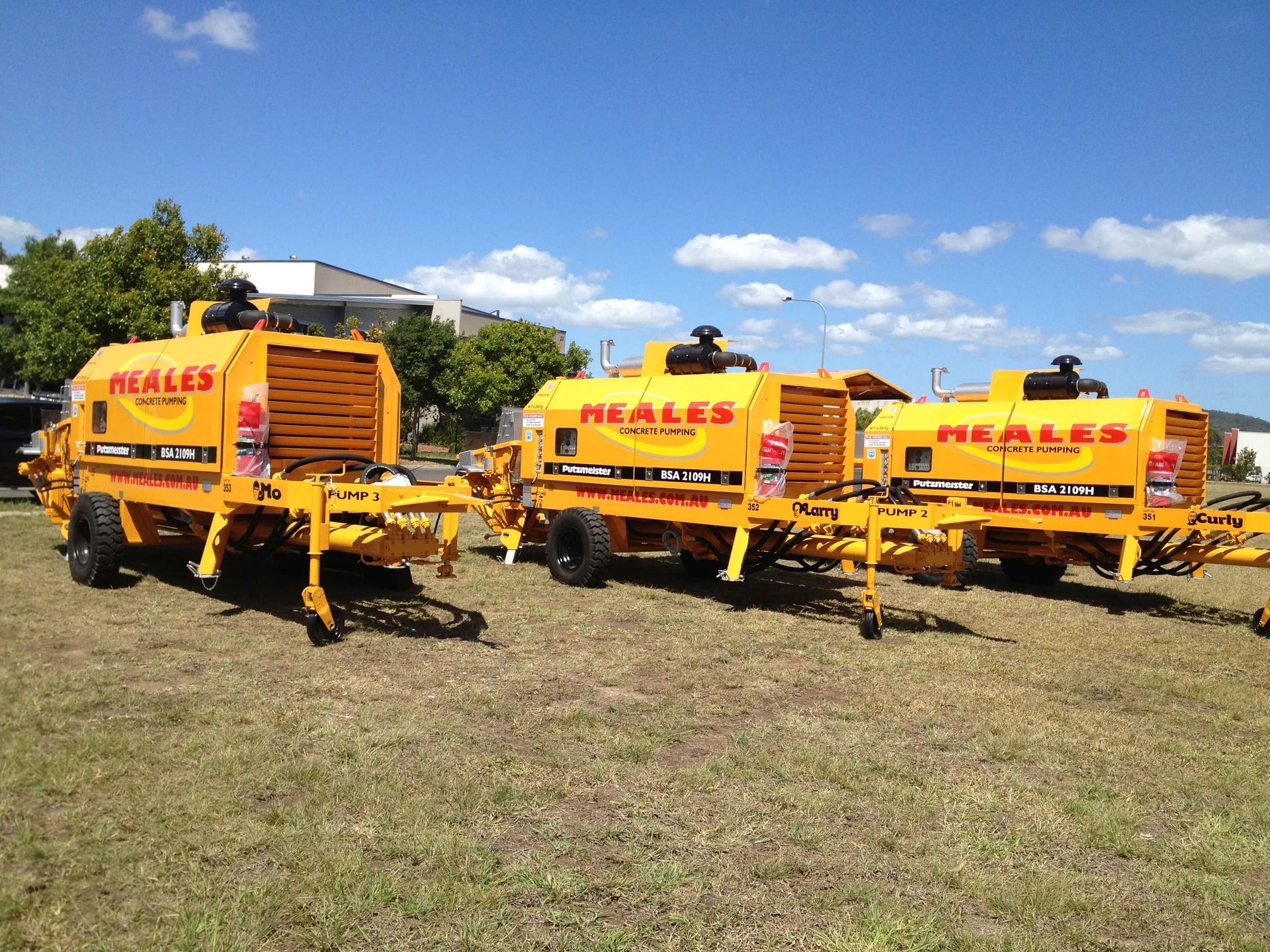 Three reales concrete pumps are parked in a grassy field